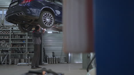 General-Plan-The-mechanic-inspects-the-exhaust-system-of-the-car-in-the-car-service.-Car-on-the-lift-inspection-and-diagnosis-of-problems-with-the-suspension-of-the-car